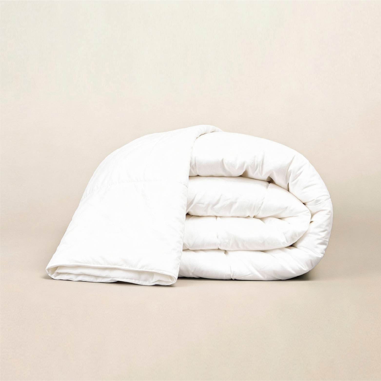 A neatly folded pristine white duvet insert resting on a neutral background