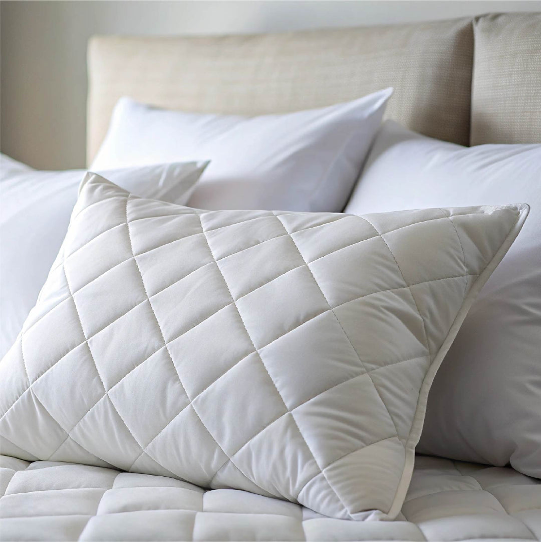 Close-up of a high-quality white quilted pillow protector on a comfortable bed.