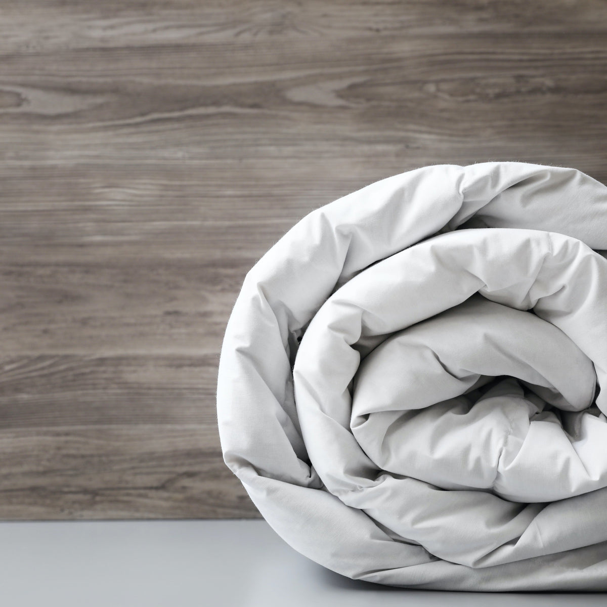 9 Tog Cloud Soft Duvet rolled up against wooden background