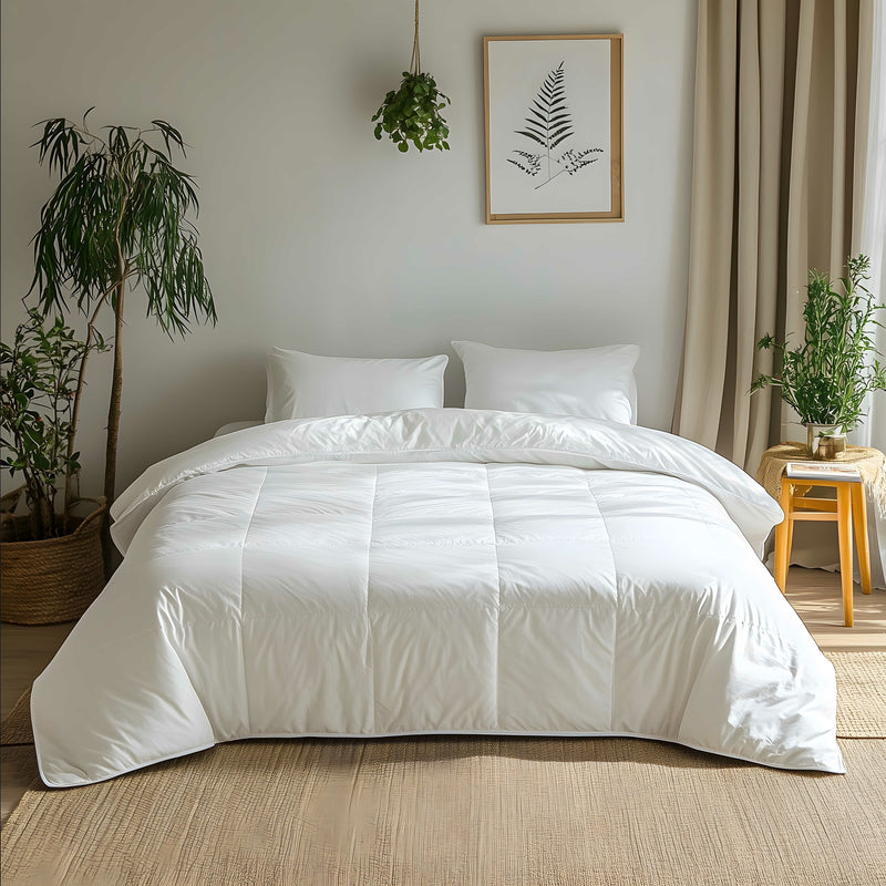 Rohi 4.5 Tog hungarian white goose feather & down duvet presented on a bed in a room with a light interior, alongside pillows, with a plant and framed picture in the background.