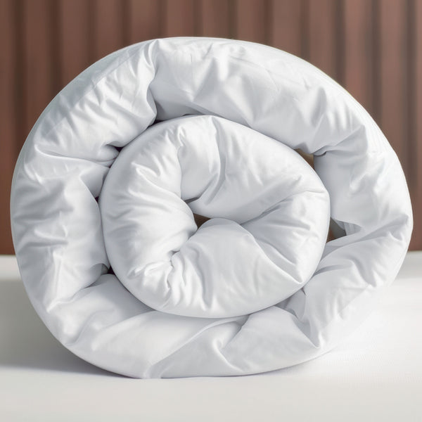 A rolled up white cotton blend duvet displayed against a wooden backdrop.